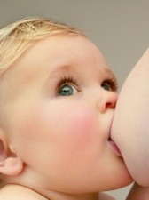 Baby boy (9-12 months) breast feeding, looking up, close-up